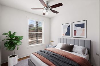 A bedroom with a bed, a ceiling fan, and a potted plant. at Mirabelle Luxury Apartments, Missouri